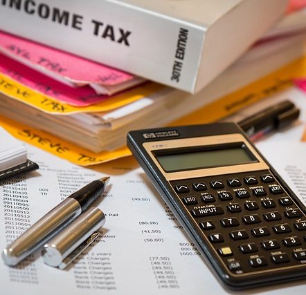 Income tax books, Calculator, Accounting papers and pen laying over