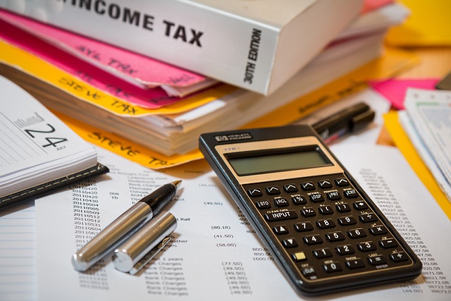 Income tax books, Calculator, Accounting papers and pen laying over