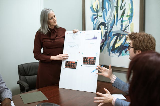 Woman Holding a White Board Paper and discussing with collogues