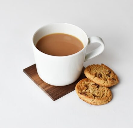 mug with coffee and two cookies on brown coaster